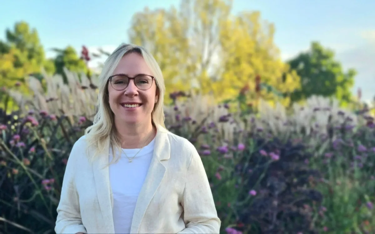 Kerstin Wiechmann lächelnd vor hohen Gräsern und violett blühenden Stauden